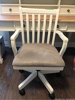 Front view of white wooden office chair with beige cushioned seat in an office setting.