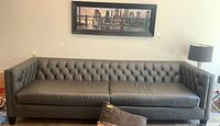 Full front view of gray leather sofa under framed artwork