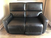 Frontal view of black leather loveseat with both seats upright