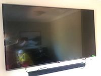 front view of 65" LG flat screen television mounted on wall above black soundbar