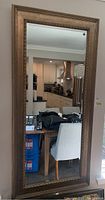 Full front view of large rectangular mirror hanging on wall reflecting kitchen interior