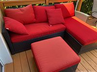 Overall view of the three-piece set: lounger, two-seater sofa, ottoman with red cushions on deck