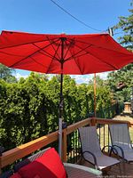 Open red patio umbrella showing fabric canopy and metal ribs, outdoors on a deck with patio furniture