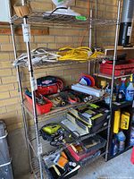 Front angled view of the metal shelving unit in a garage setting with various tools and items on shelves, showing the shelving structure and wear.