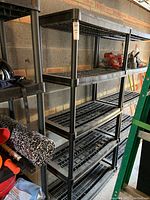 Front angled view of the black plastic shelving unit showing five shelves and vertical posts.