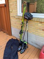 Full view of ski set including skis, poles, boots, helmet, and pants arranged on decking.