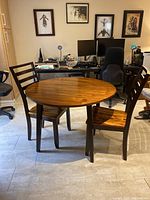 Round wood table with two matching wood chairs viewed from front in room setting