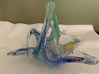 Side view of free form Murano basket with handle showing colorful swirl pattern and label