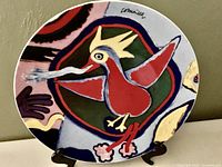 Front view of the circular ceramic plate prominently showing the red firebird and artist signature