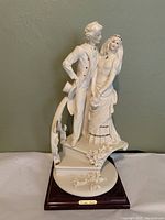 Front view of the white porcelain bride and groom figurine standing on stairs with floral details, showing textured dress and gold accents.