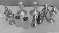 Full view of all items showing the candlesticks and four pairs of salt and pepper shakers arranged in a line.