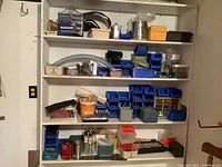 Shelves filled with multiple small bins, containers, and assorted hardware and tools including nails, screws, and boxes of supplies.