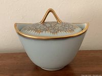 Side view of celadon blue porcelain vegetable bowl with gold patterned lid and gold rim