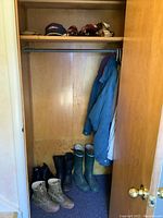 Photo of closet with boots on floor and coats hanging inside