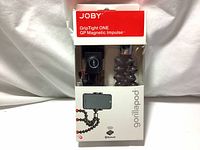 Front view of original packaging showing the Joby Grip Tight ONE GP Magnetic Impulse Gorillapod tripod and Bluetooth remote inside.