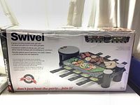 Box displaying the Swissmar Swivel 8-person raclette grill with product details and images of the grill cooking various foods on granite and aluminum plates.