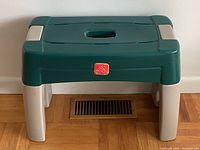 Front view of the green and beige Step2 garden kneeler seat showing the padded sitting/kneeling surface and molded handle on top.