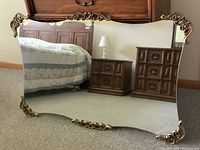 Front view of the large mirror showing its reflective surface and gold decorative accents.