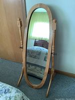 Front view of the full length oval cheval mirror showing wooden frame, stand, and oval reflective surface.