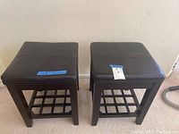 Front view of two dark brown leather cushioned wooden stools with grid lattice base visible.