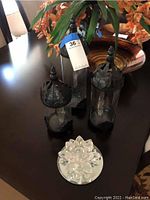 Set of three glass candle holders with black metal leaf tops and crystal lotus candle holder on mirror