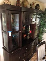 Front angled view of the dark wood china cabinet showcasing the glass display doors with decorative grid overlay, drawers below, and cabinet structure.
