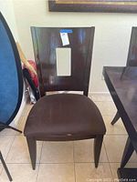 Full view of one dark wood dining chair showing shape, style, and upholstery color.