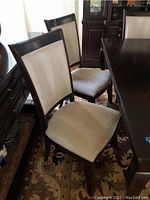 Photo of two high back dining chairs with light beige chenille upholstery and dark wood frames.