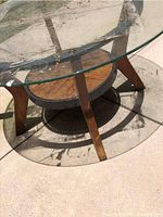 Top angled view of round glass table showing water damage and wooden legs.