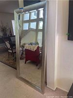 Front view of the large silver framed mirror showing its size and reflective surface within a home interior setting.