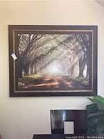Frontal view of large framed wall art painting showing tree-lined path and light filtering through branches.