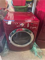 Front view of red Maytag dryer in a cluttered storage area.