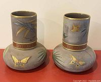 Front view of two Asian style ceramic vases with bird and butterfly paintings, gold accents.