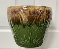 Front view showing embossed sun and moon design with green glaze and brown drip glaze above