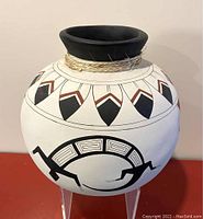 Front and side view of signed Mexican terracotta vase with black flared rim and geometric designs