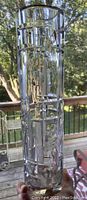 Photo showing the tall cylindrical shape of the clear glass vase with geometric circular and diamond pattern embossing