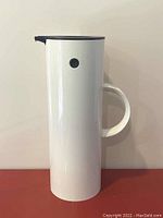 Photo showing the full front side view of the white cylindrical vacuum jug with black rocker stopper lid and handle.