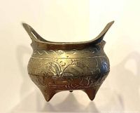 Full side view of the brass tripod censer showing engraved dragon and wave patterns and three legs.