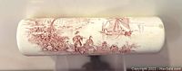 Top side image of the porcelain rolling pin showing red Victorian-style transferware design with figures, buildings, and a ship.