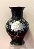 Front view of black brass vase with mother of pearl floral inlay design.