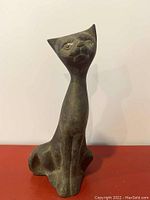 Front view of vintage brass Siamese cat figurine showing the elongated neck, detailed facial features, and seated pose.
