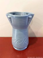 Front view showing blue ceramic Art Deco vase with ribbed and wave design, flared rim, and side handles.