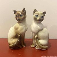 Front view of a pair of vintage Siamese cat salt and pepper shakers with detailed features and crackled glaze.