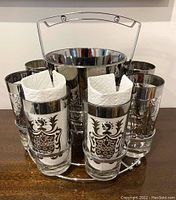 Photo showing six vintage glass highball tumblers with silver overlay in metal caddy with silver-toned ice bucket in center.
