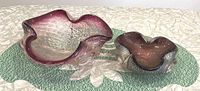 Two Murano glass bowls shown side by side, highlighting their size difference and distinctive shape and coloring.
