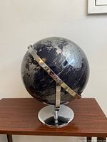 Front view of black globe with chrome base on wooden table, showing Africa and surrounding regions.