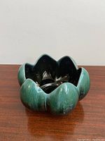 Lotus shaped planter with green gradient glaze and lotus petal design sitting on a wooden surface.