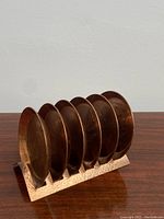 Six copper coasters displayed upright in hammered copper stand showing animal etchings on each coaster.