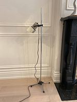 Full view of chrome floor lamp showing cubist style angular lamp head, slender chrome pole, tripod base, and black adjustable arm.