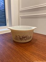 Full view of beige Pyrex casserole dish with speckled pattern, mushroom design around sides, and integrated handles.